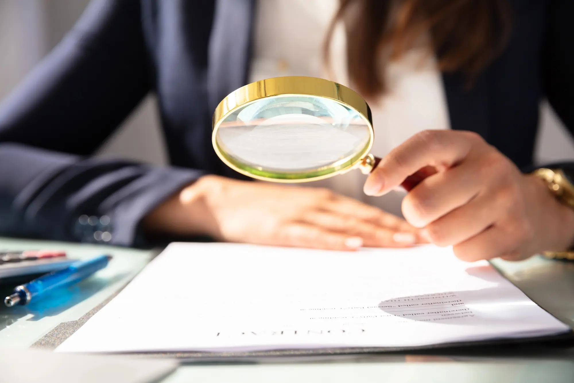 Landlord closely inspecting a rental application with a magnifying glass, symbolizing detailed tenant screening process