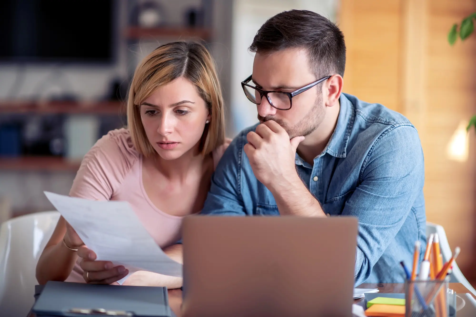 Worried couple reviewing an eviction notice at home with financial documents and laptop on table