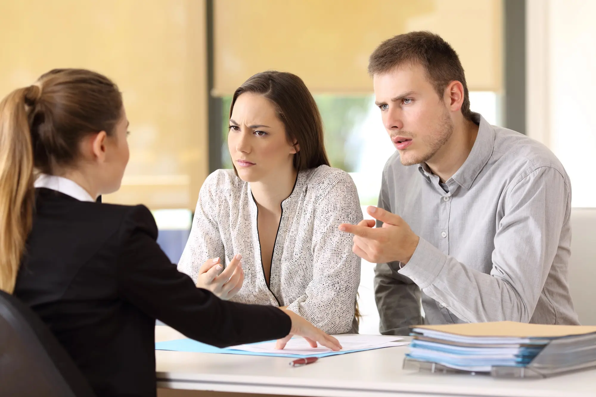 Frustrated tenants speaking with a landlord or mediator across a desk during a dispute resolution meeting