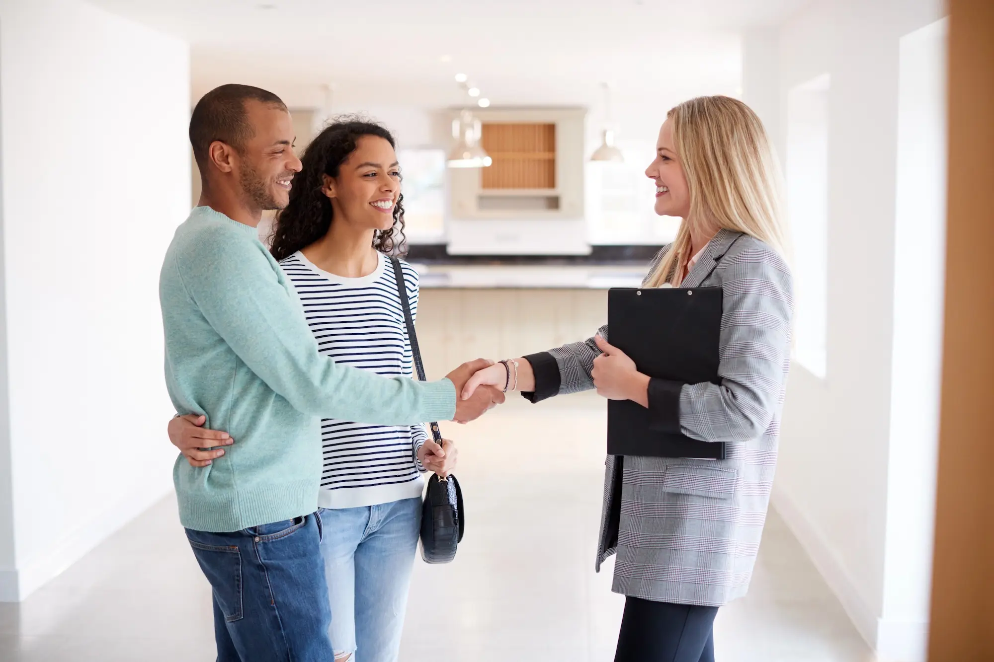 Couple shaking hands with a property manager in a rental kitchen after reviewing lease terms