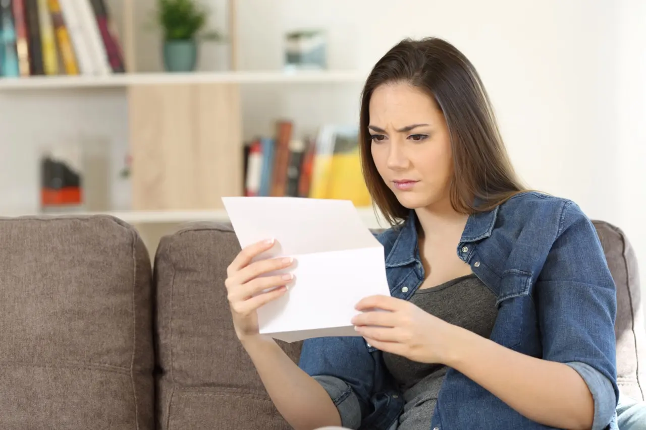 Woman reading a rental application denial letter with a concerned expression