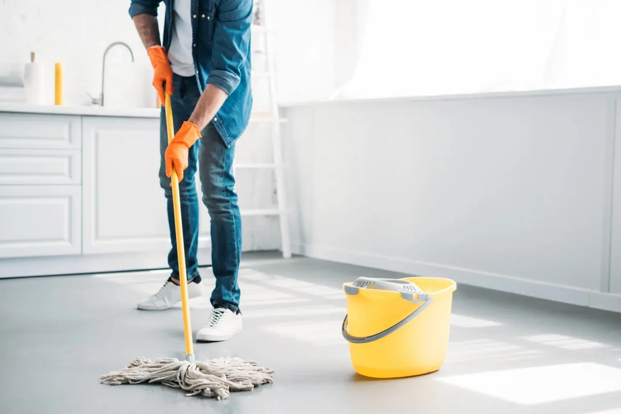 Renter cleaning an empty apartment by mopping the floor before moving out