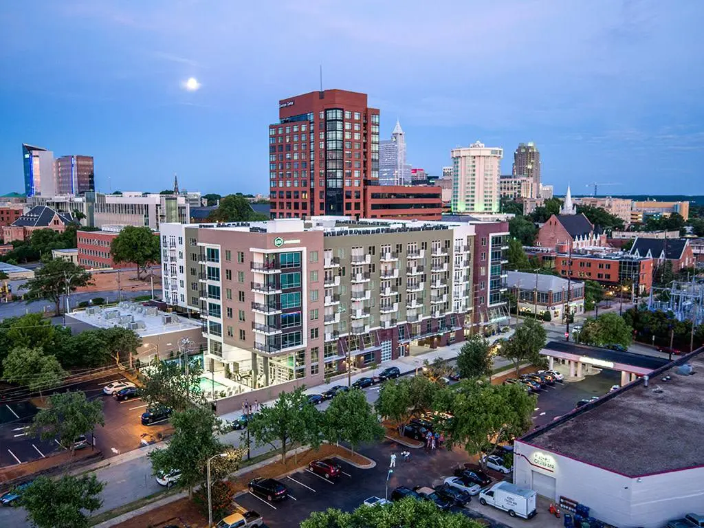 Mid-rise apartment complex in Raleigh with visible parkingnearby streetsand surrounding buildingsillustrating typical urban rental conditions