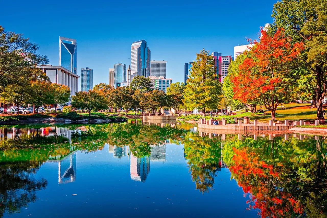 Charlotte skyline reflected in a park pond near Uptown, showing green space and city living
