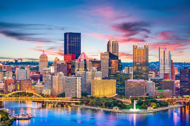 Downtown Pittsburgh skyline at sunset with Point State Park and the river in the foreground